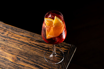 Refreshing drink with orange slices on a wooden table in a dimly lit setting © Serega