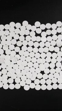 Vertical video: Entering white discs moving inward on overhead dark mat, forming dense central band