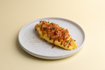 Fototapeta premium Delicious omelet topped with salmon and sauce served on a white plate on a light background