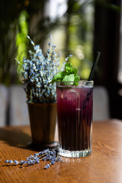 Refreshing drink with mint and lavender placed on a wooden table in a bright indoor setting