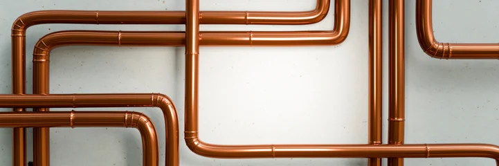 Polished copper pipes arranged in a complex network against a textured wall © Studio-FI