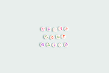 Obraz premium Drink some water. Quote made of white round beads with multicolored letters on a blue background.