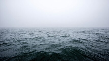 Fototapeta premium Foggy ocean horizon with textured water surface and gentle waves. Moody seascape with soft gray tones and peaceful ambiance. Natural background with minimal composition