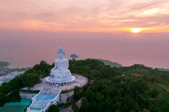 Aerial top sunset view magnificent white marble Buddha statue sits serenely atop a lush Phuket hilltop