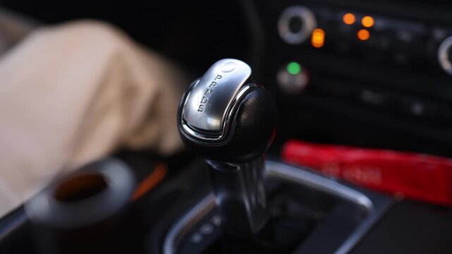 Close-up of woman hand with ring shifting automatic transmission gear selector to drive mode in car. Perfect for automotive, driving and transportation themed commercial projects