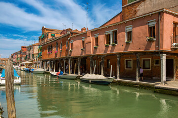 Obraz premium Scenic canal view in Venice, Italy, with moored motorboats and terracotta facades