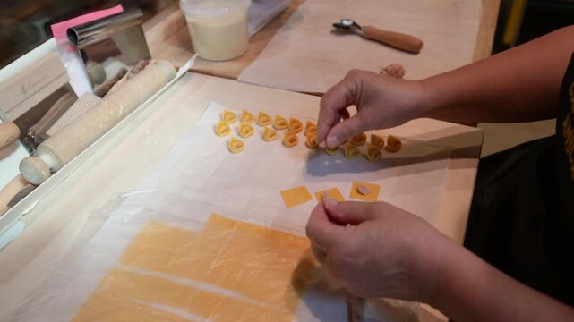 Modena, italy, april 11, 2026. Skillful hands of a chef meticulously folding and shaping traditional italian tortellini pasta, preparing a delicious, authentic meal