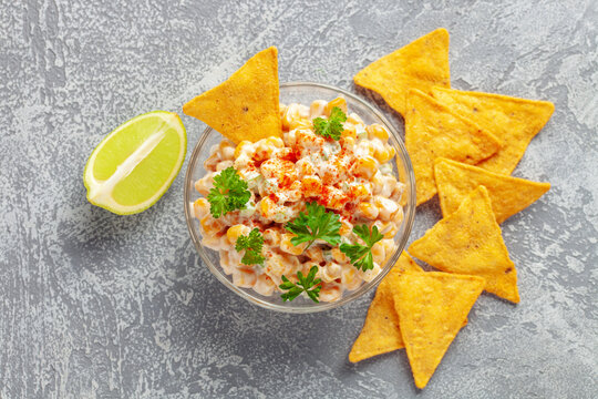 Mexican street corn dip in bowl. Elote dip with nachos chips. Latin American cuisine. Top view