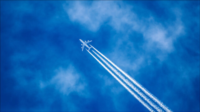 Airplane Ascending into Blue Sky with White Contrails: Dynamic Motion Captured in Professional Aviation Photography