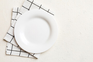 Naklejka premium Top view on colored background empty round white plate on tablecloth for food. Empty dish on napkin with space for your design
