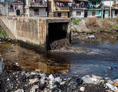 Polluted river with trash and buildings.