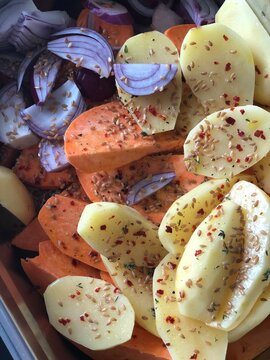 Delicious close-up view of seasoned sweet potatoes, potatoes and onions, prepared for roa