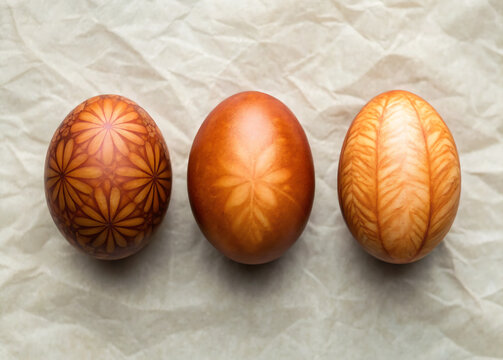 Three copper easter eggs with botanical leaf pattern on crumpled paper detail