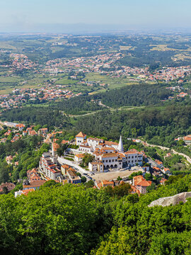Sintra cityscape and National Palace, white building with conical chimneys from the mountain top. Town Palace is the best-preserved medieval royal residence in Portugal. The blend of Gothic, Manueline