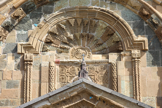 Gandzasar monastery exterior showcases 12th century armenian architecture with ornate stone carvings, khachkars and religious reliefs on a weathered, historic facade