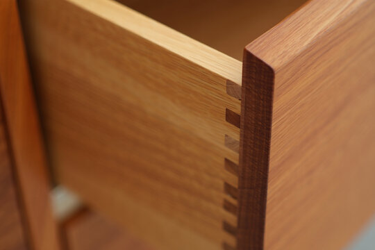 Detailed view of interlocking dovetail joints on natural wood drawer construction showcasing craftsmanship and skilled woodworking techniques