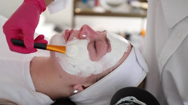 Aesthetician carefully applies an even layer of clay mask to the client's face, providing deep cleansing and balancing for the skin