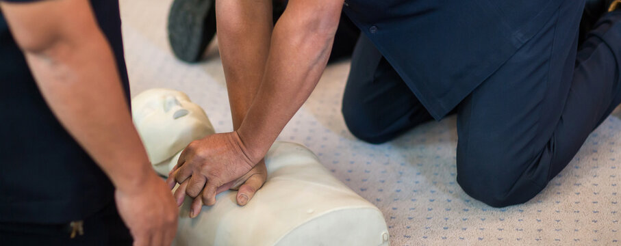 CPR training using and an AED and bag mask valve on an adult training manikin.  First aid cardiopulmonary resuscitation course using automated external defibrillator device, AED.