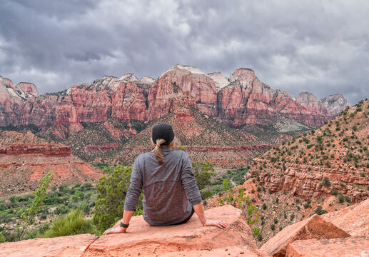 Woman sitting on a cliff looking out over Zion National Park