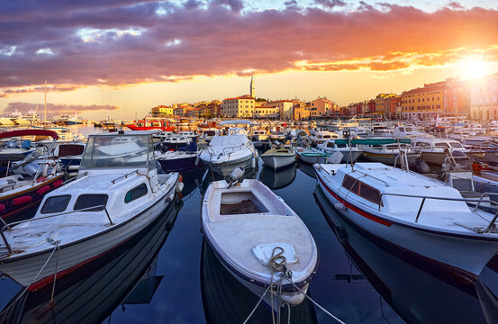 Rovinj, Istria, Croatia. Motorboats and boats in port of Rovigno. Medieval vintage houses of old town. Yachts landing, high tower of Church of Saint Euphemia. Morning sunrise blue sky with clouds..