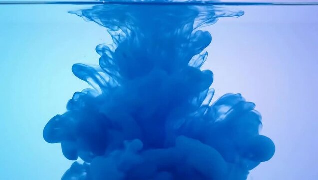 Vibrant blue ink cloud swirling and dissolving in clear water creating abstract fluid art patterns