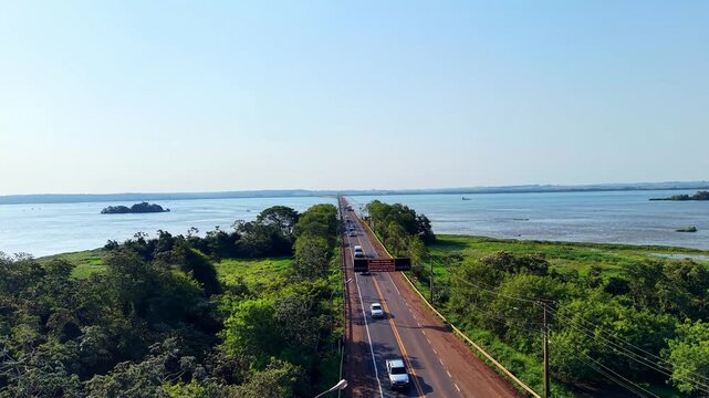 Aerial drone takeoff revealing Ayrton Senna Bridge over Paran&aacute; River, connecting S&atilde;o Paulo and Mato Grosso do Sul, Brazil, with vehicles crossing a long highway bridge.
