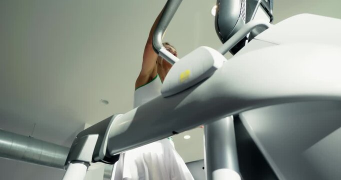 Woman Exercising on Elliptical Machine at Gym