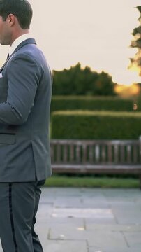 Vertical video: Clasping hands at sunset, man in grey suit swaying with partner on stone terrace