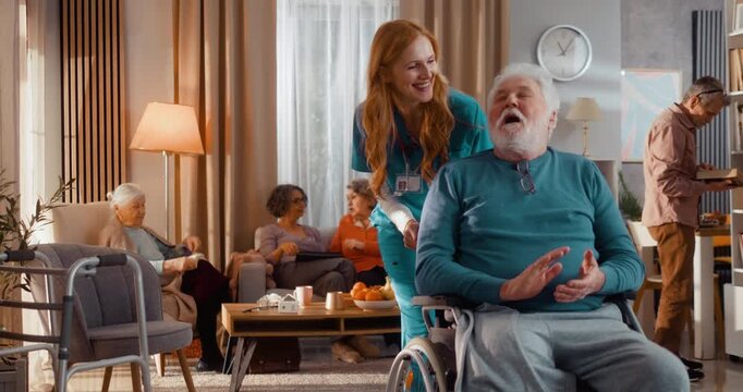 Kind caregiver pushing elderly man in wheelchair with amputated leg in assisted living home. Warm interaction, support and communication, promoting mobility and inclusion indoors.
