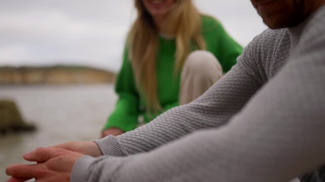 Woman in green sweater looks distressed while by the ocean with a man