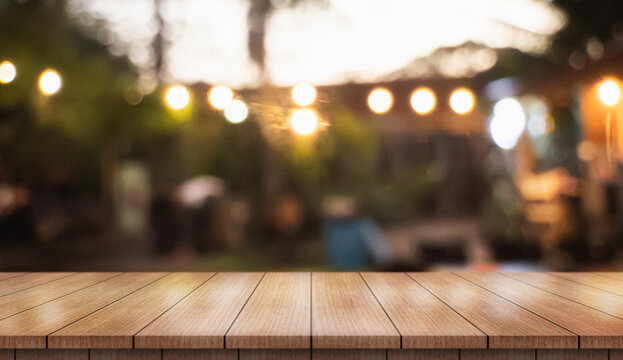 Empty wooden table top with lights bokeh on blur restaurant background.
