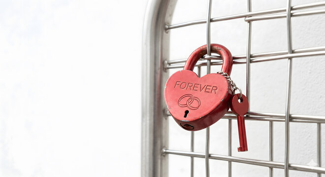 Heart Shaped Red Love Lock and Key on Metal Grid with White Background. Conceptual Image Symbolizing Romance and Fidelity.