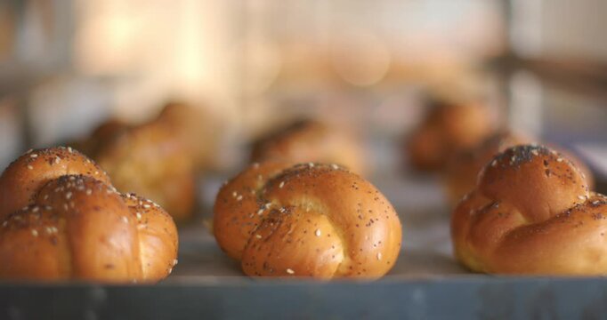 Lens shifting focus and exposure, bringing front braided roll sharp on tray, showing seeded crust