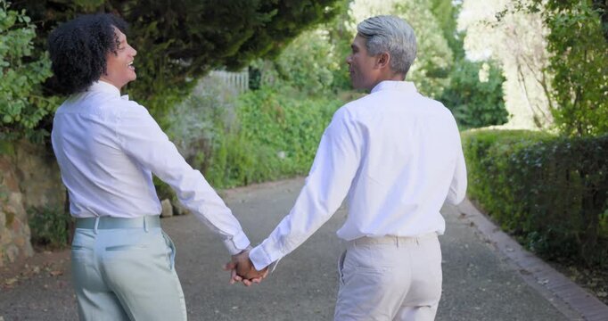 Sunlit path drawing African American couple holding hands walking talking in white shirts smiling
