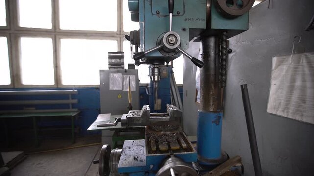 An industrial drilling machine idling in a workshop in a workshop.