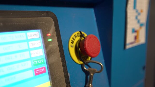 The control panel displays various functions and an emergency button inside the machine located in the workshop.