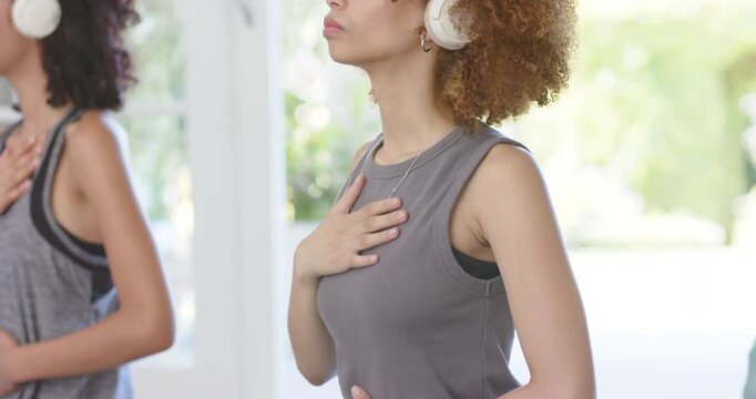 African American women following audio via white headphones, breathing slowly for calm by windows