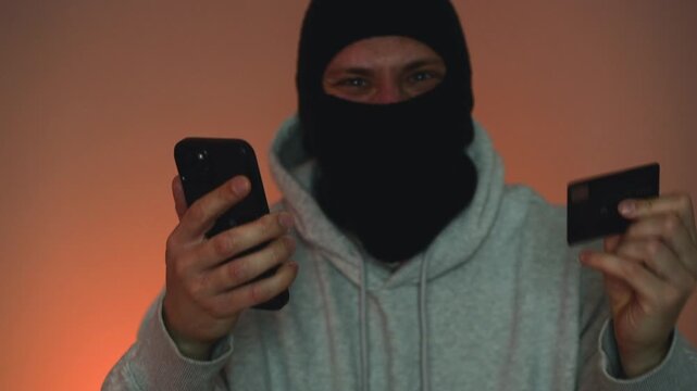 A masked robber enters a credit card PIN, a financial scam.
Illegal theft of money from a bank account.