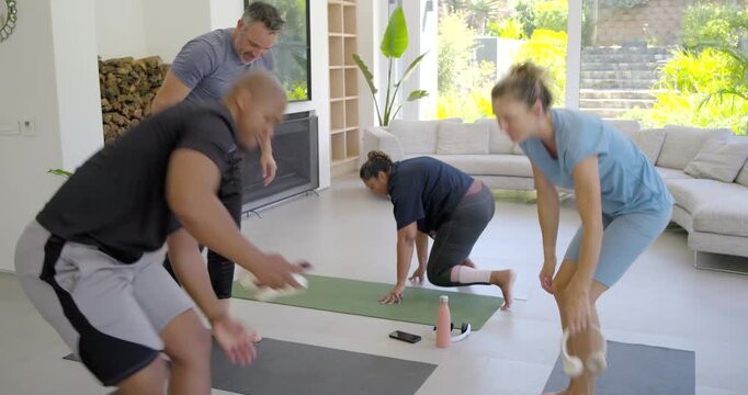 Four yoga participants finishing session at home, having brief chat, rolling mats, preparing to go