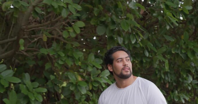 Adult man standing by shrub in yard hearing sound, turning scanning, smiling laughing in white T