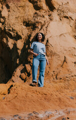 Naklejka premium Woman stands confidently on vibrant red rock cliffside