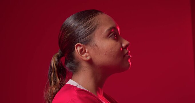 African American adult woman turning profile to frontal on studio cue for portrait, in red jersey