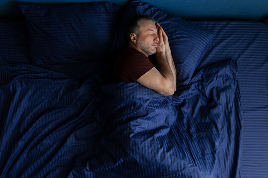 Middle aged man sleeping peacefully on side with hands under head