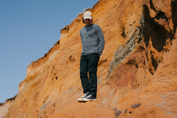 Man stands atop vibrant, sunlit cliffside © Reuben