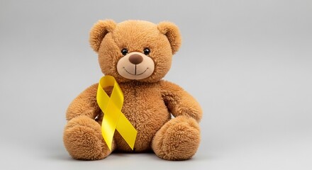 Fototapeta premium Teddy bear with yellow awareness ribbon symbolizing support for childhood cancer and hope featuring stuffed animal, plush, charity with remembrance