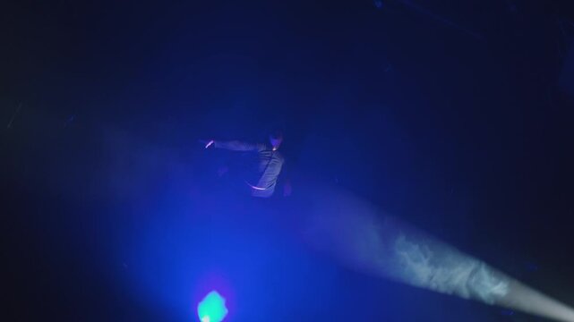 Overhead cinematic video of a young man falling backward into deep darkness, surrounded by glowing blue smoke. Represents failure, surrender, or dreaming.