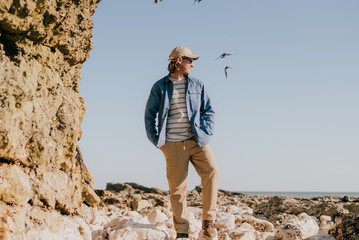 Man stands on rocky shore, gazing toward ocean © Reuben