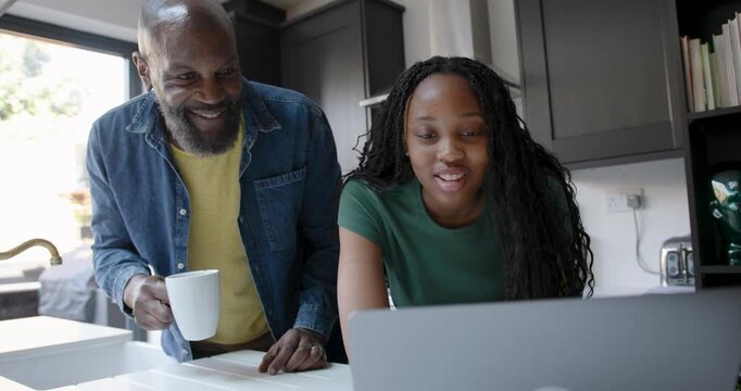 Father Supporting Child Education in Kitchen with Laptop computer Technology