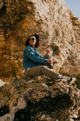 Naklejka premium Woman smiles warmly, seated on rocky cliffside
