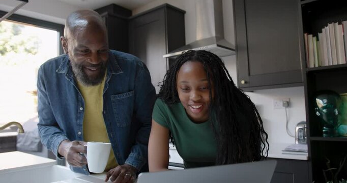 Father Supporting Child Education in Kitchen with Laptop computer Technology